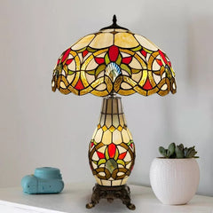 A beautifful vinatge multicolor stained glass tiffany style cluster table lamp of 16 inch is placed on a white table beside a potted plant