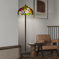 A beautiful floral stained glass 16 inch tiffany floor lamp placed beside a chair and table