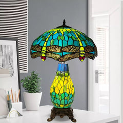 A beautiful green and lime color tiffany cluster table lamp with a metal base placed on a white table