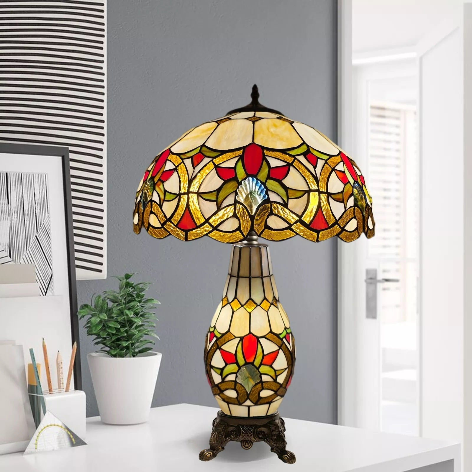 A multicolor 16 inch Tiffany style cluster table lamp with a stained glass shade and a metal base, displaying a geometric pattern, placed on a white surface in a room.