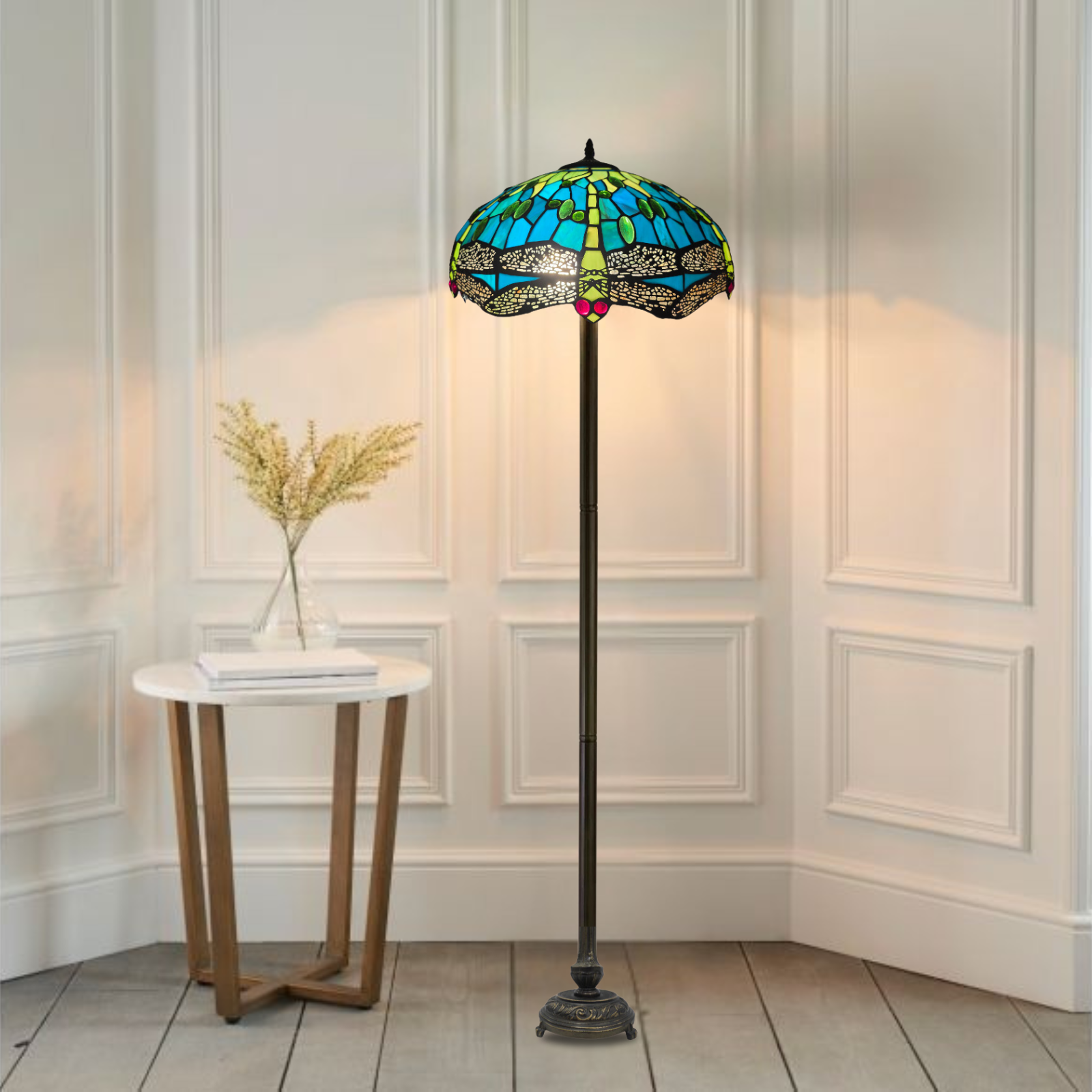 A beautiful grreen color stained glass large tiffany floor lamp placed in a white background room baside a table