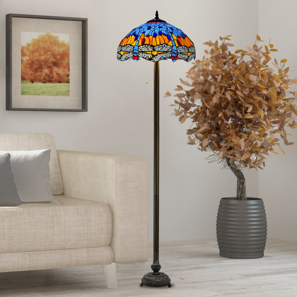 A Tiffany style floor lamp with a blue and orange stained glass shade, standing in a room with a neutral interior. The lamp is switched off, showing the colorful pattern of the glass.