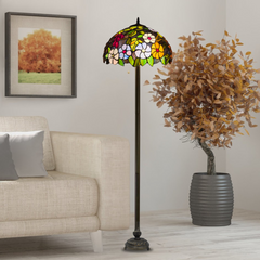 A beautiful stained glass floral 16 inch tiffany floor lamp placed in a living room beside sofa and potted plant