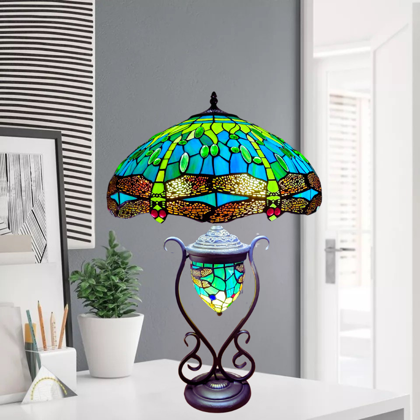 A beautiful green and blue tiffany style handmade stained glass 18 inch cluster table lamp with metal base placed on a desk 